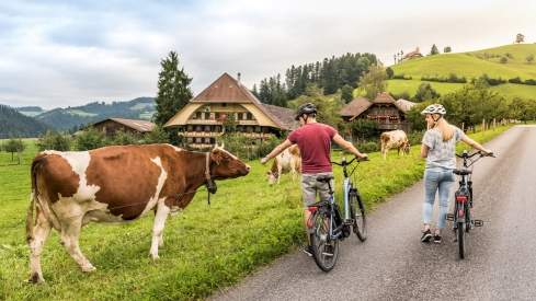 Paar mit Kühen vor einem traditionellen Emmentaler Bauernhaus