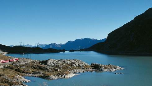 Der Bernina Express entlang des Lago Bianco im Sommer. 